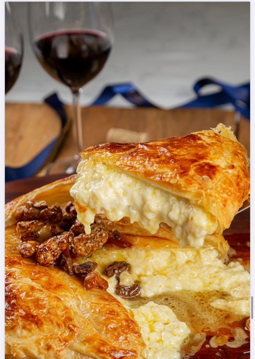 Brie 1kg folhado cortado, mostrando o queijo cremoso por dentro com castanhas caramelizadas e mel